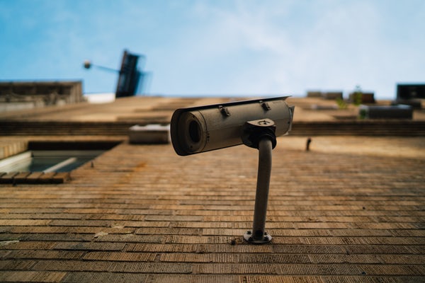 Looking up at security camera mounted on a brick wall with blue sky in the background.