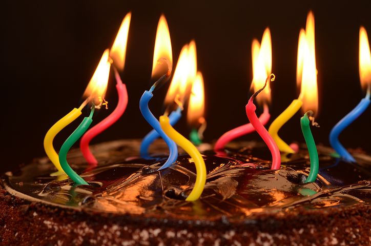 Many colorful lit candles on a chocolate birthday cake.