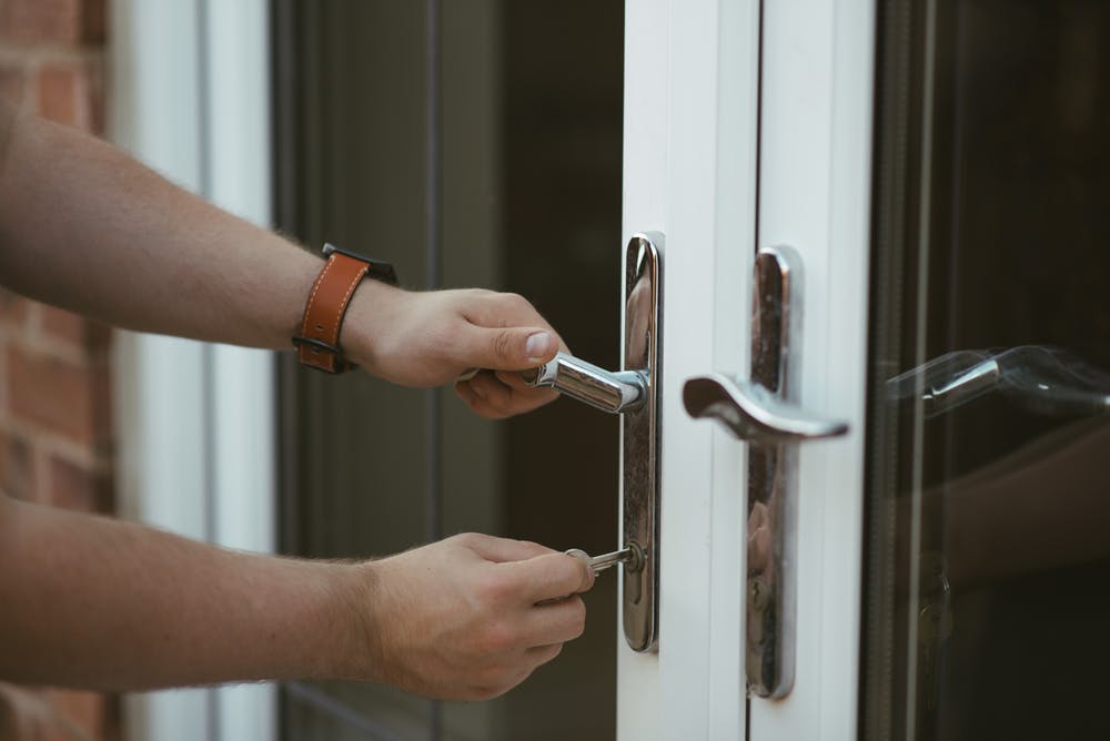 A person locking or unlocking a double door.