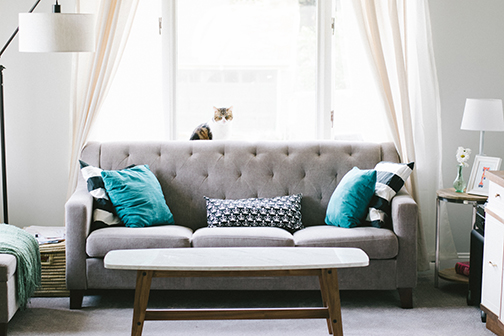 a nice couch, table, lamps, and a window in an apartment perfect for an apartment security system.