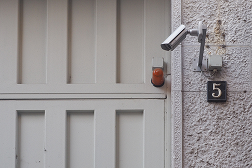 Security camera mounted on the wall next to a garage.