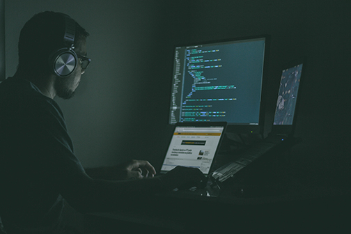 Programmer programming virtual security on his computer with several monitors.