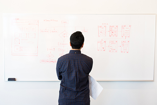 Man looking at white board with a security plan drawn up. 