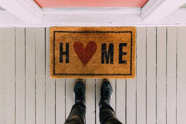 home doormat with red heart forming the O