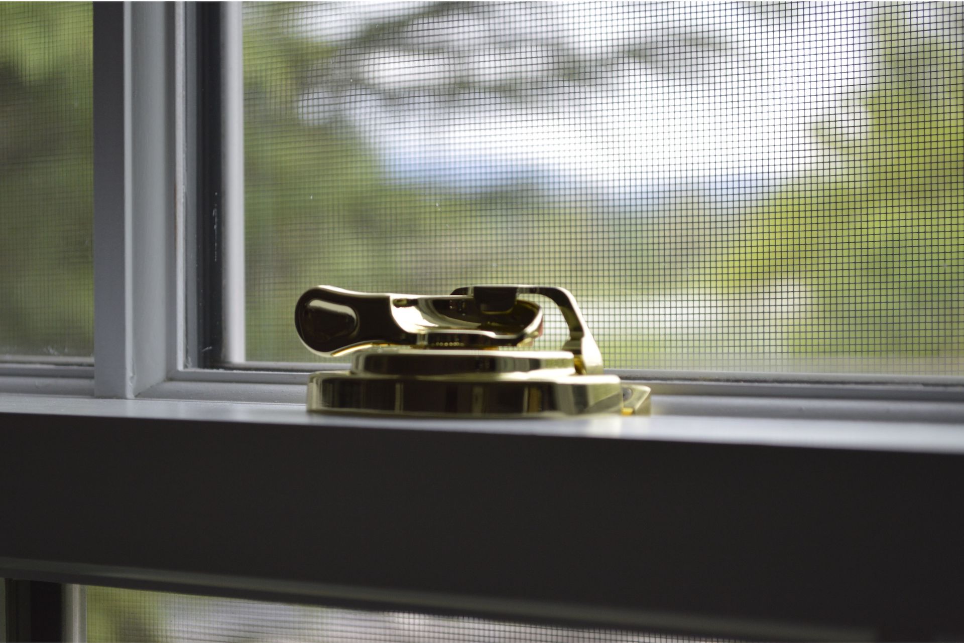 Close up of a Nice Window Lock. Blurred trees in the background. 