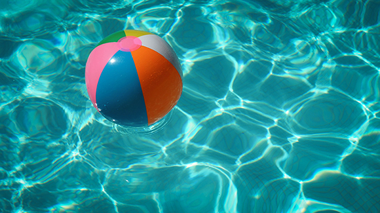 multicolored beach ball floating in clear blue swimming pool