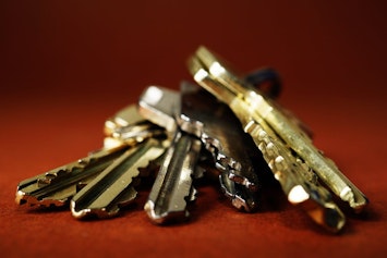 A ring of keys lying on their side with a red background behind it. 