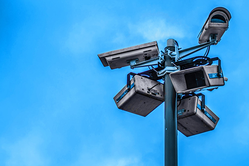 Several huge cameras facing different directions at the top of a long pole. The blue sky is the background.