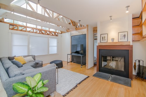 Living Room with a grey loveseat, fireplace, tv and natural lighting coming from the ceiling.