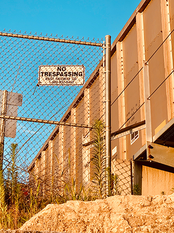 No Trespassing Sign on chainlink fence at Sunset next to concrete building