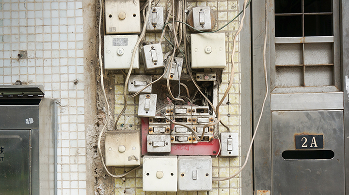 Tons of electrical wires and switches on a wall. Looks like it could lead to a class c electrical fire.