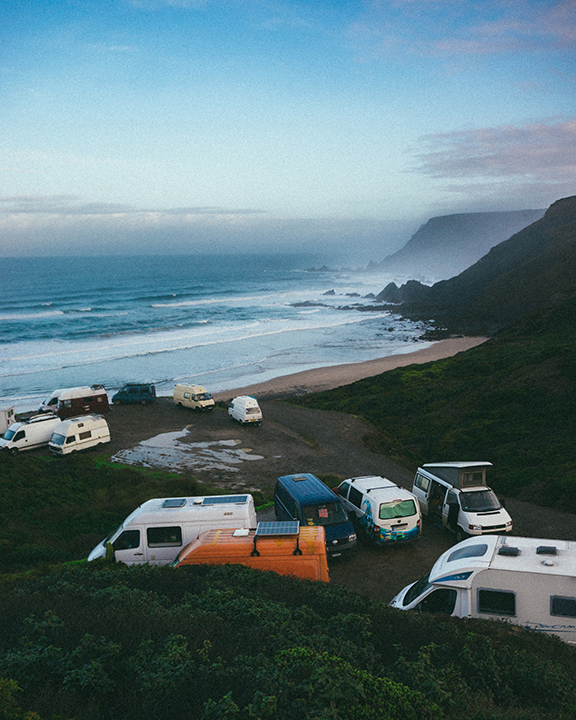 Several different RVs parked near the beach. Blue ocean in the background with a light layer of white fog.
