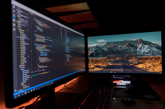 ONVIF code can be seen on one monitor. The other monitor has an image of a desert and a mountain in the background