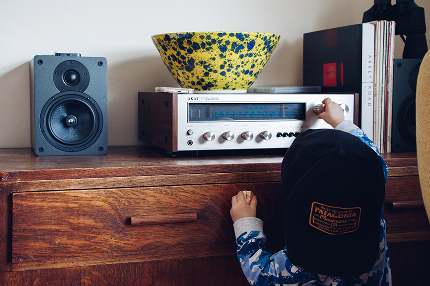 Child with hat on backwards turning on the radio.