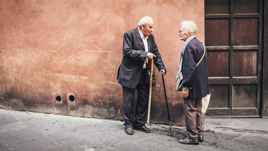 An old man and old woman talking on the street that might benefit from having personal alarms for the elderly.