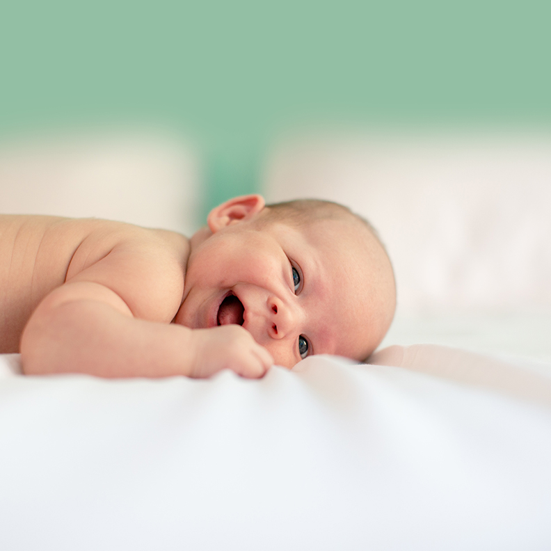 Baby Laying Down and Smiling at Camera