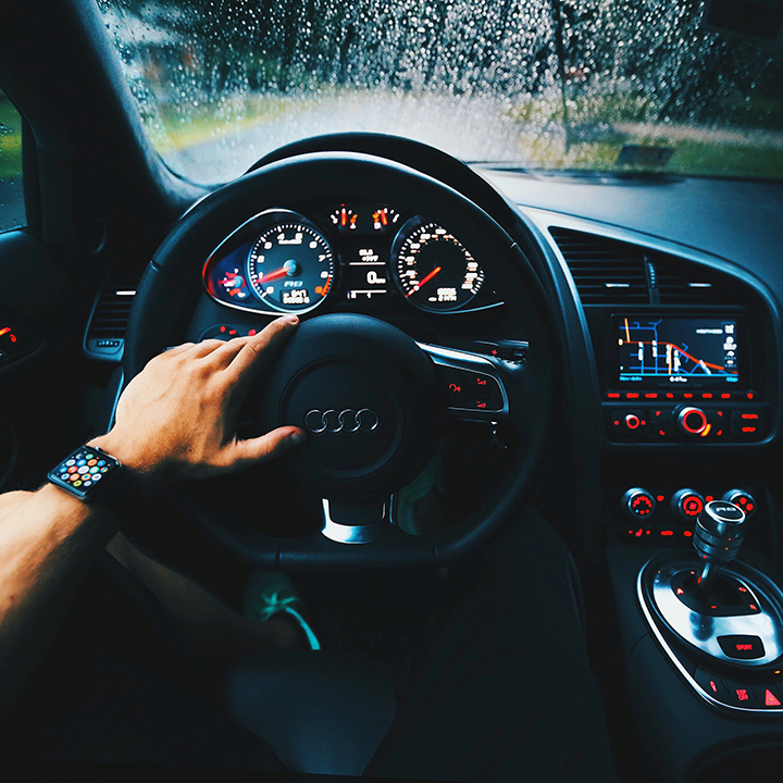 Man's arm on the steering wheel of a nice car that deserves an anti theft device steering wheel lock.