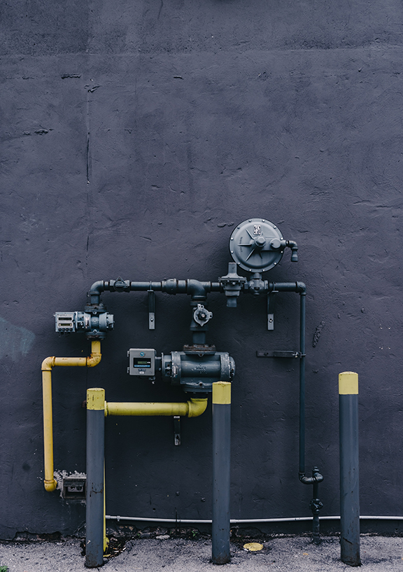 Water Pipes painted Yellow and Black Sticking Out of the Side of a Black Wall