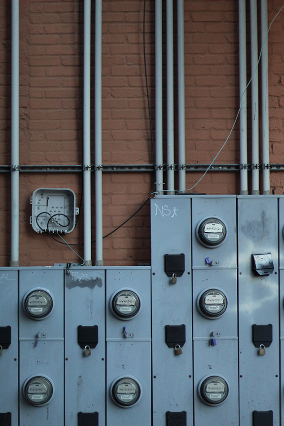 pipes and gauges mounted on the outside of a brick wall.