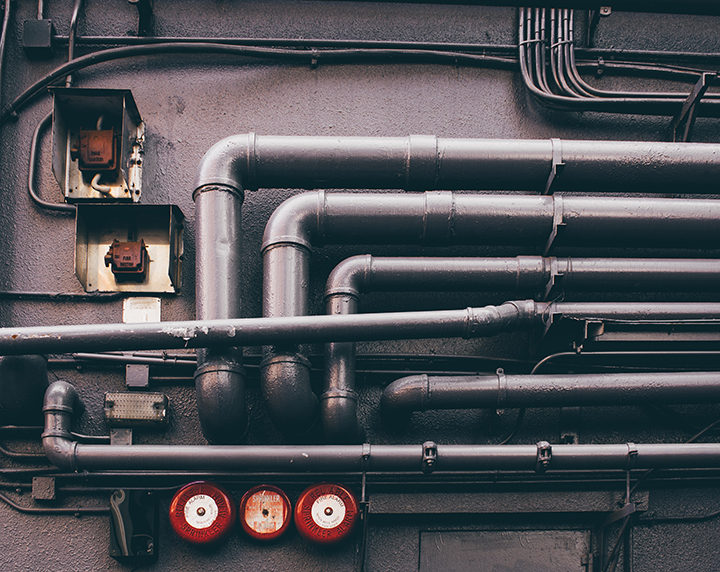 Grey pipes going a wall.