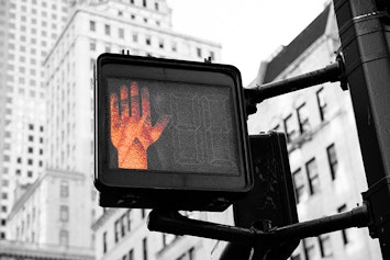 crosswalk stop hand on sign signifying safe precautions and tips.