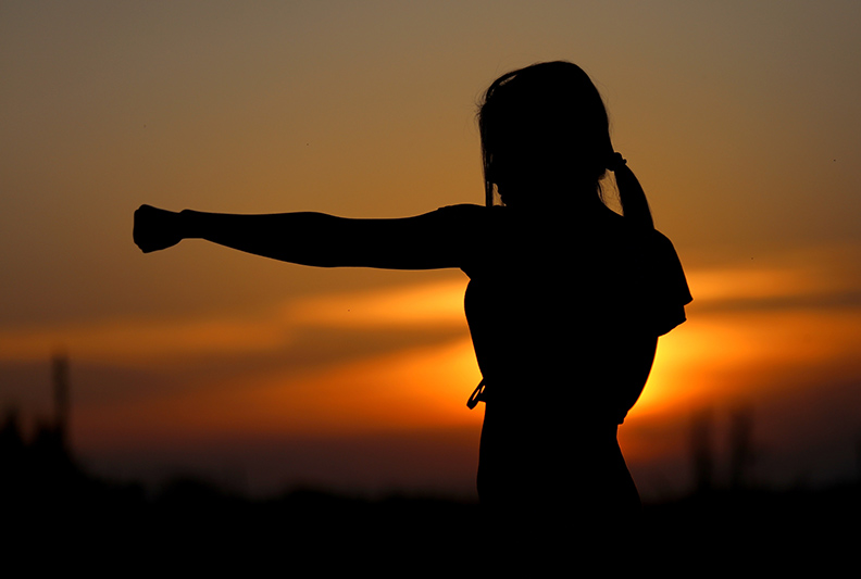 Silhouette of person practicing self defense in the light of sunset.