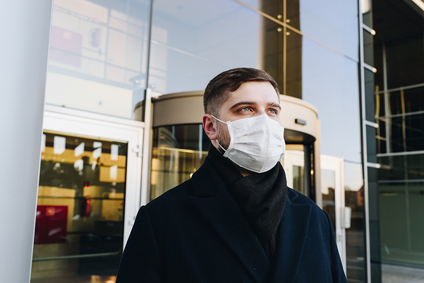 Man Wearing Surgical Mask in front of glass building.