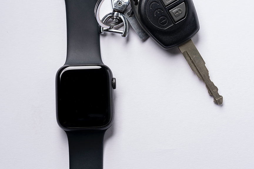 Key fob and apple watch on a white background. Key fob battery waiting to be changed.