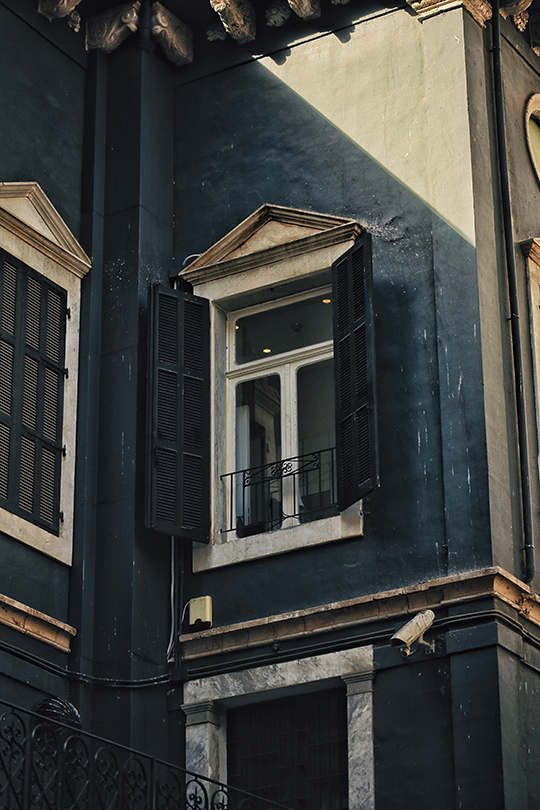 Outdoor shutters on blue painted building with a security camera
