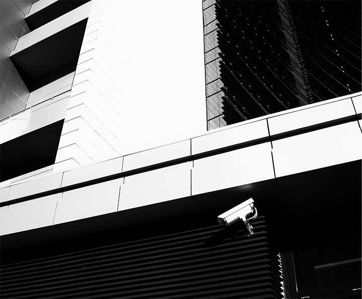 Black and White photo of. a building with a security camera attached to it.