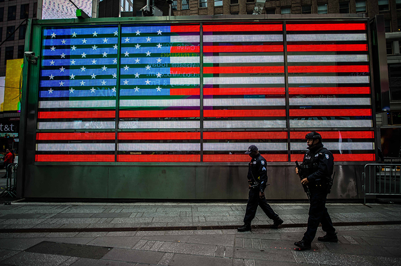 Two Police Officers in New York Walking Past an American Flag