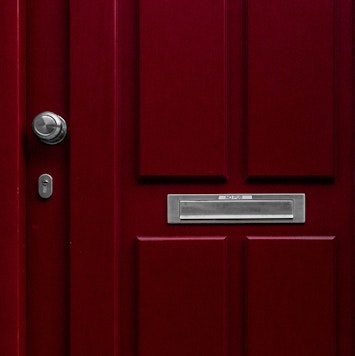 Image of a locked red door with a mail slot.