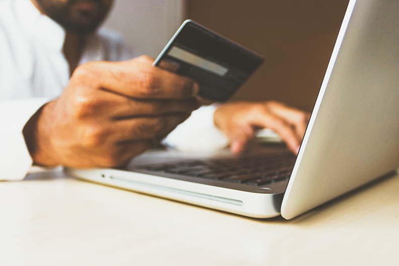 Man checking credit report with credit card and laptop.