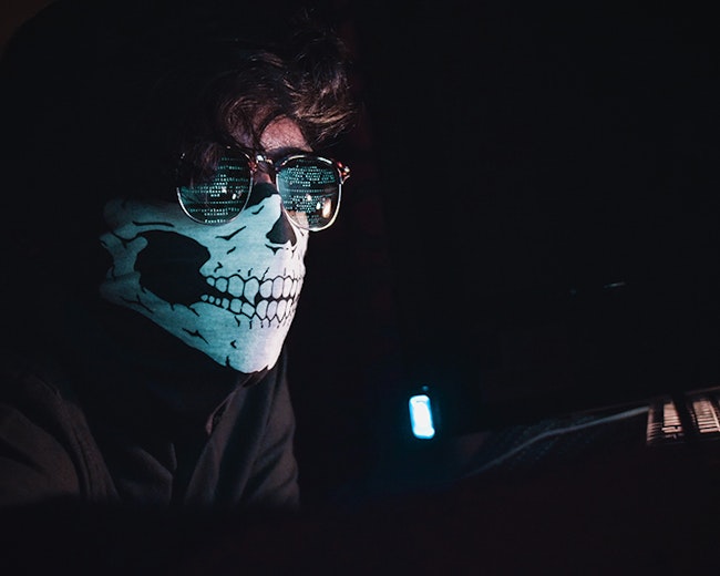 identify thief taking personal information to steal money while wearing a skeleton mask and sunglasses.