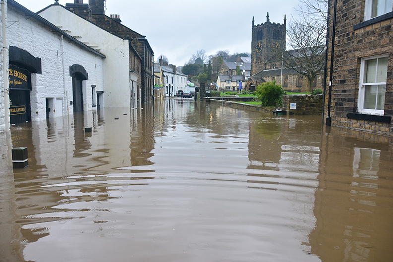 A flooded street in Europe with a cathedral in the background. 