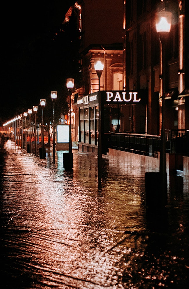 Flooded street lined with lamp posts.