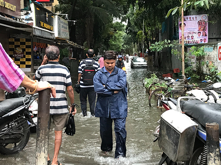 Man walking through crowded flooded street in a tropical area.