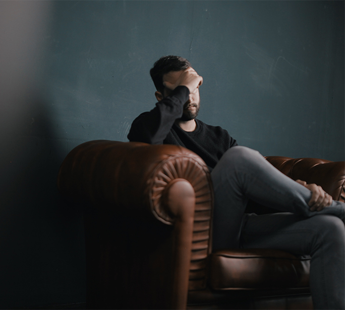 Man on couch with headache due to poor air quality.