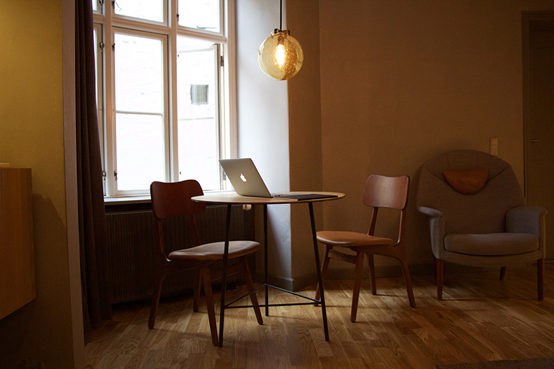 A clean apartment. Two chairs and a laptop on a table next to an open window.