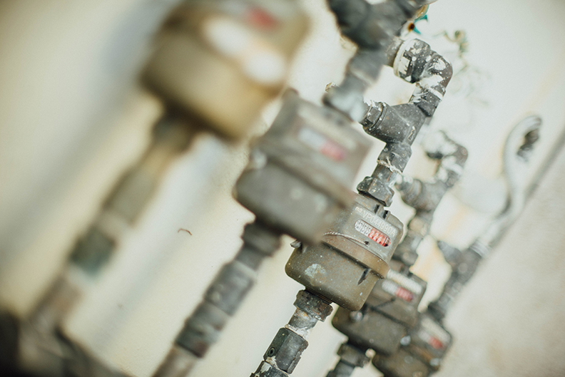 Several pipes with meters sticking out of a wall.