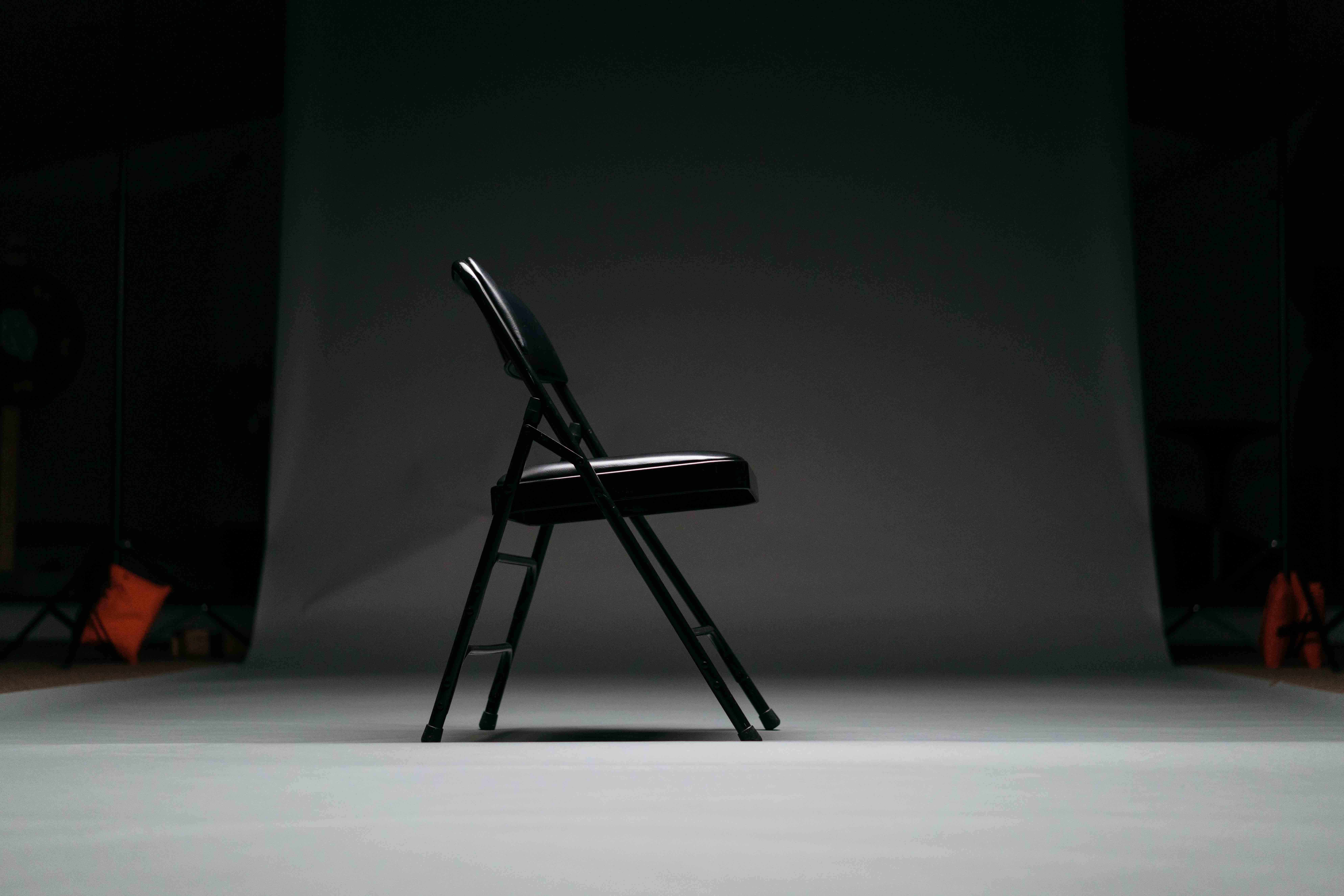 A black cushioned folding chair in a studio.