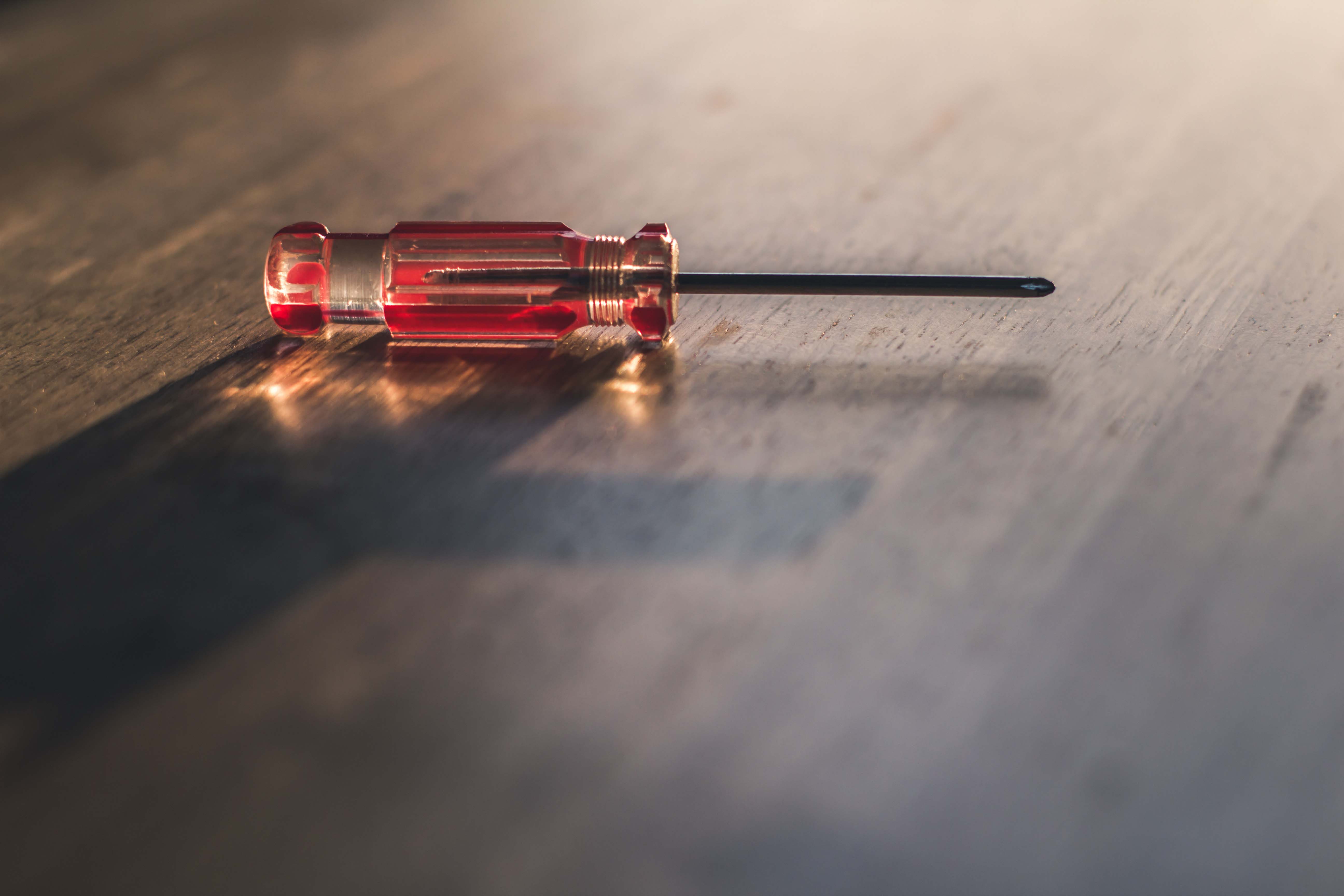 A red screwdriver on a wooden surface.