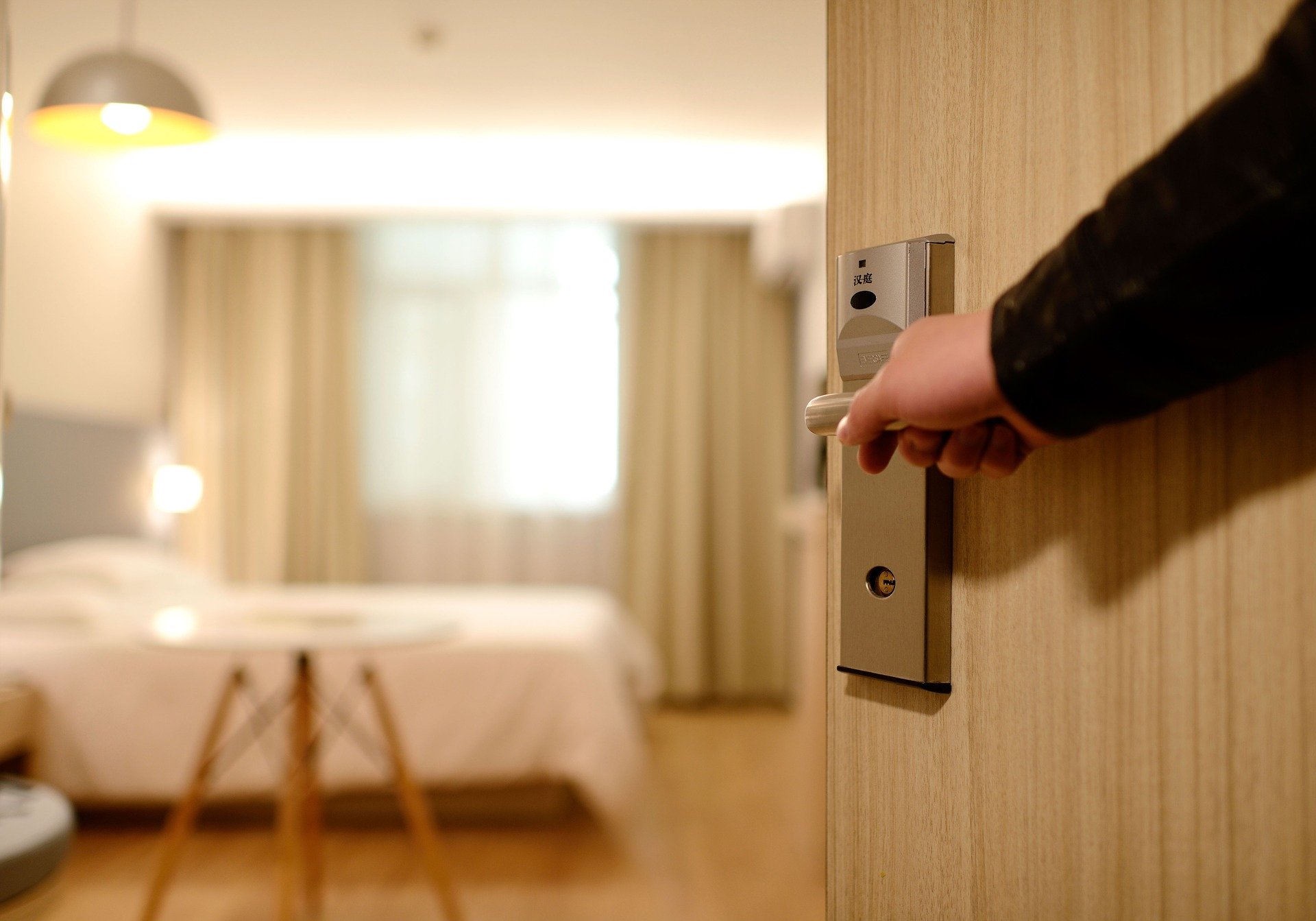 A Hand Opening a Door to a Hotel Suite.