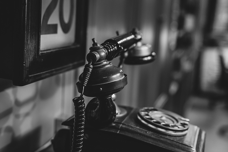 Rotary telephone on top of a bookshelf. 