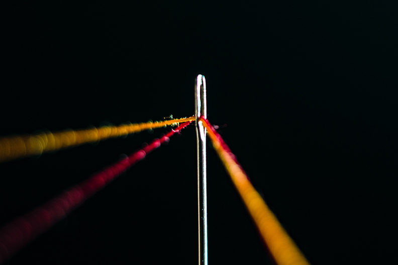 Thread going through the eye of a needle. Set up as a trip wire.