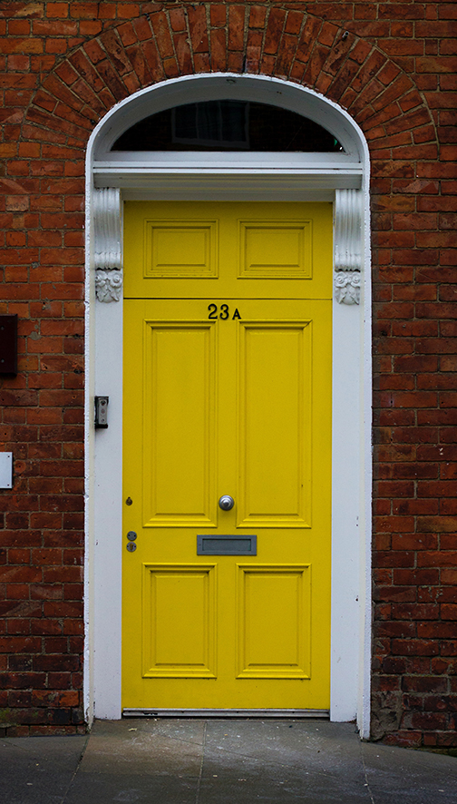 Yellow locked door set into a brick building. 