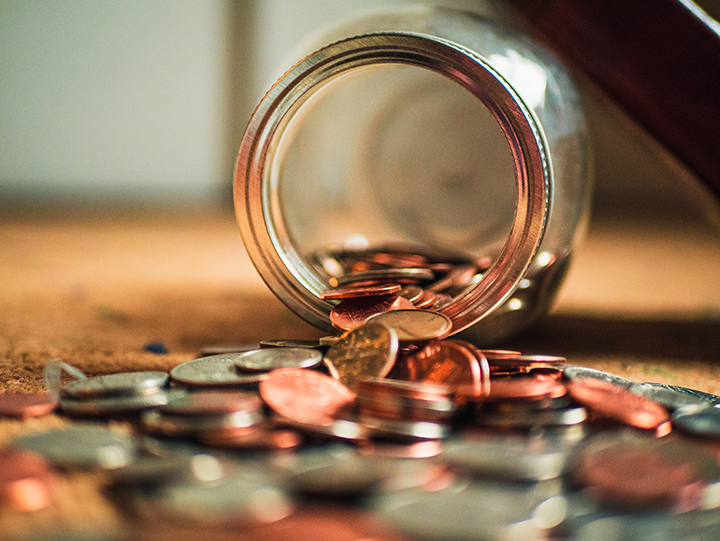 Nickles, dimes, and pennies spilling out of a coin jar.