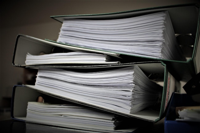 A stack of four binders full of papers