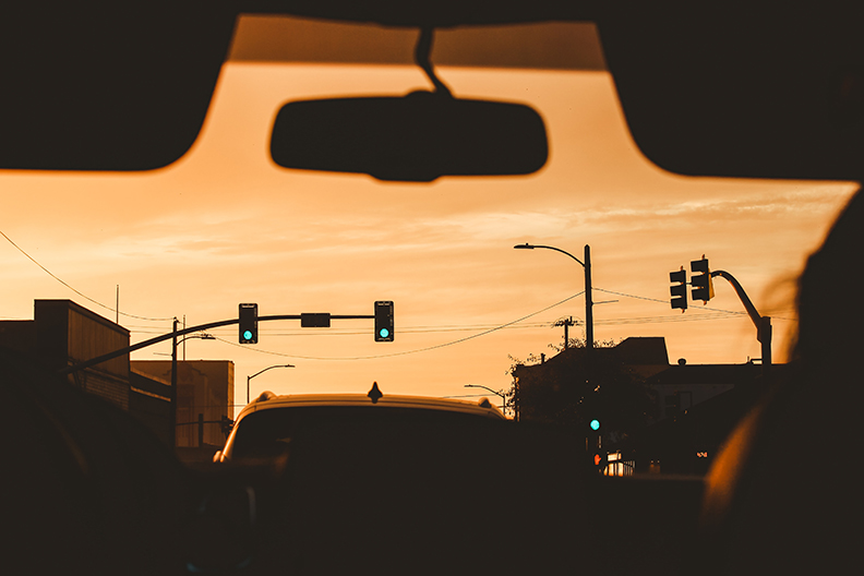 From inside of the car you can see a green stoplight at sunset in Eureka California