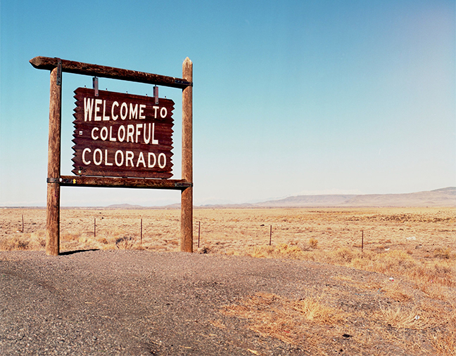 Welcome to Colorado wooden sign. Blue sky. Brown plains.